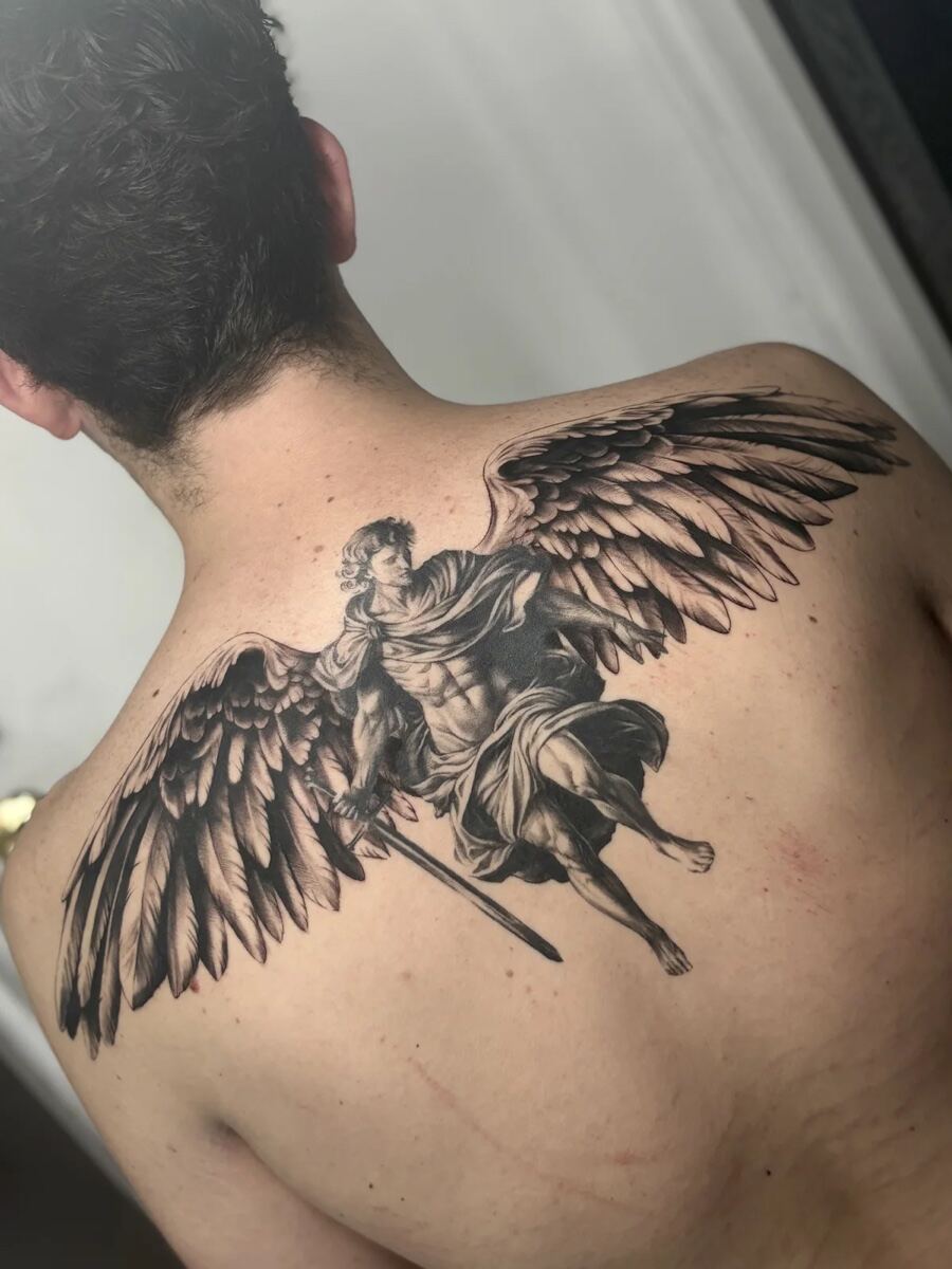 Black and grey realism back, archangel with sword and spread wings